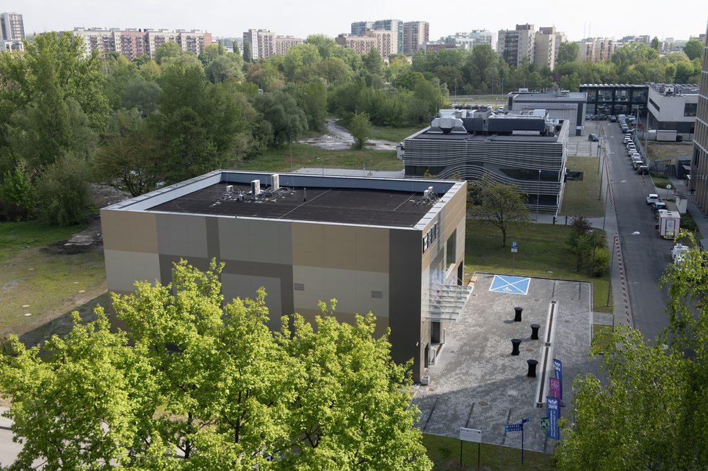 Dwa kwadratowe niskie budynki z lotu ptaka. To Laboratorium Ultraprecyzyjnych Pomiarów Współrzędnościowych oraz Laboratorium Aerodynamiki Środowiskowej. Dookoła widać drzewa, w oddali budynki osiedla.