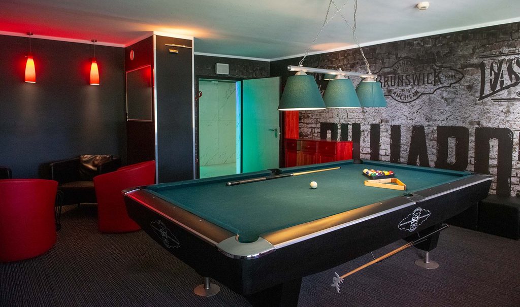 Sala bilardowa z zielonym stołem i czerwonymi meblami