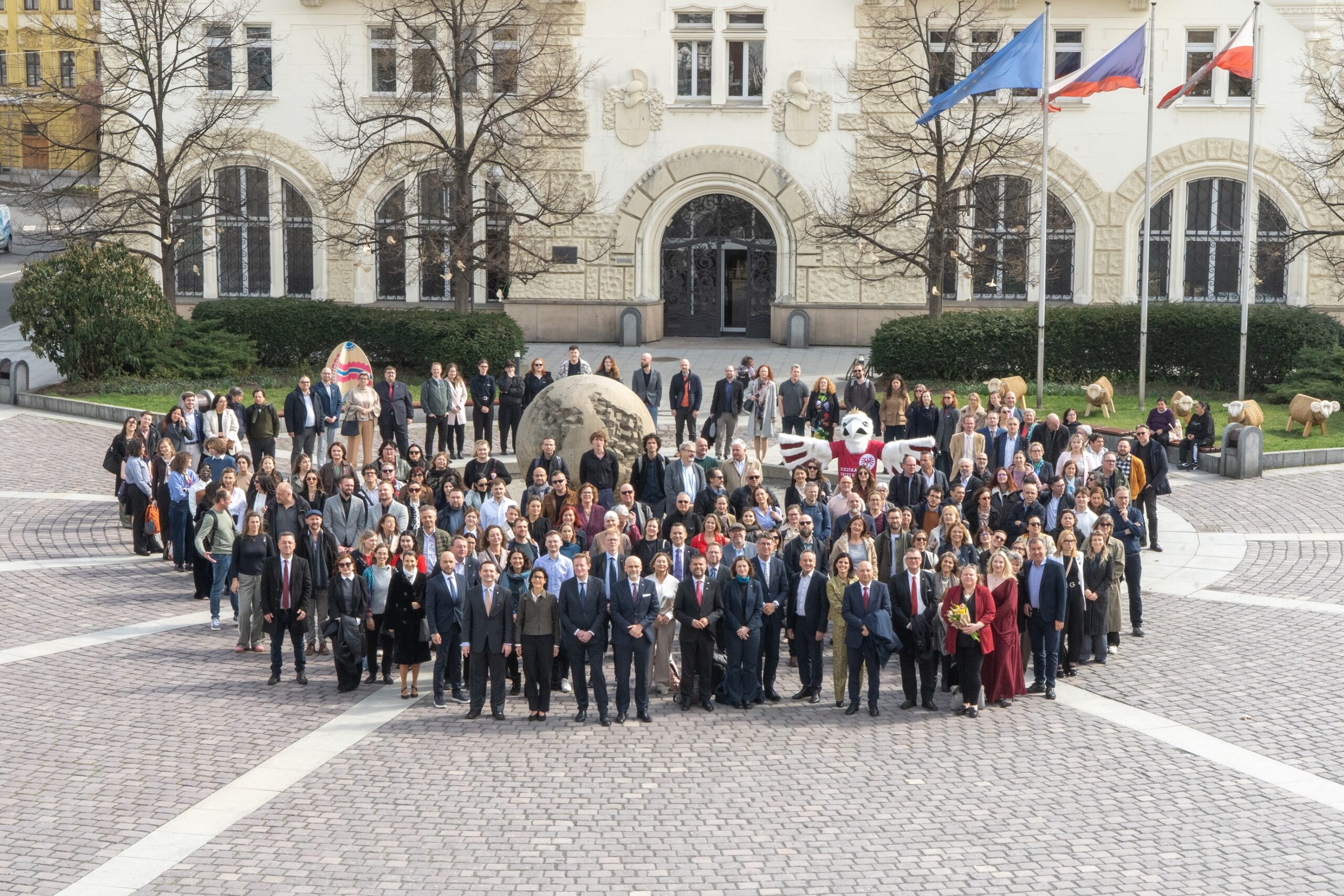 Uczestnicy konferencji pozują do wspólnego zdjęcia na dziedzińcu uniwersytetu