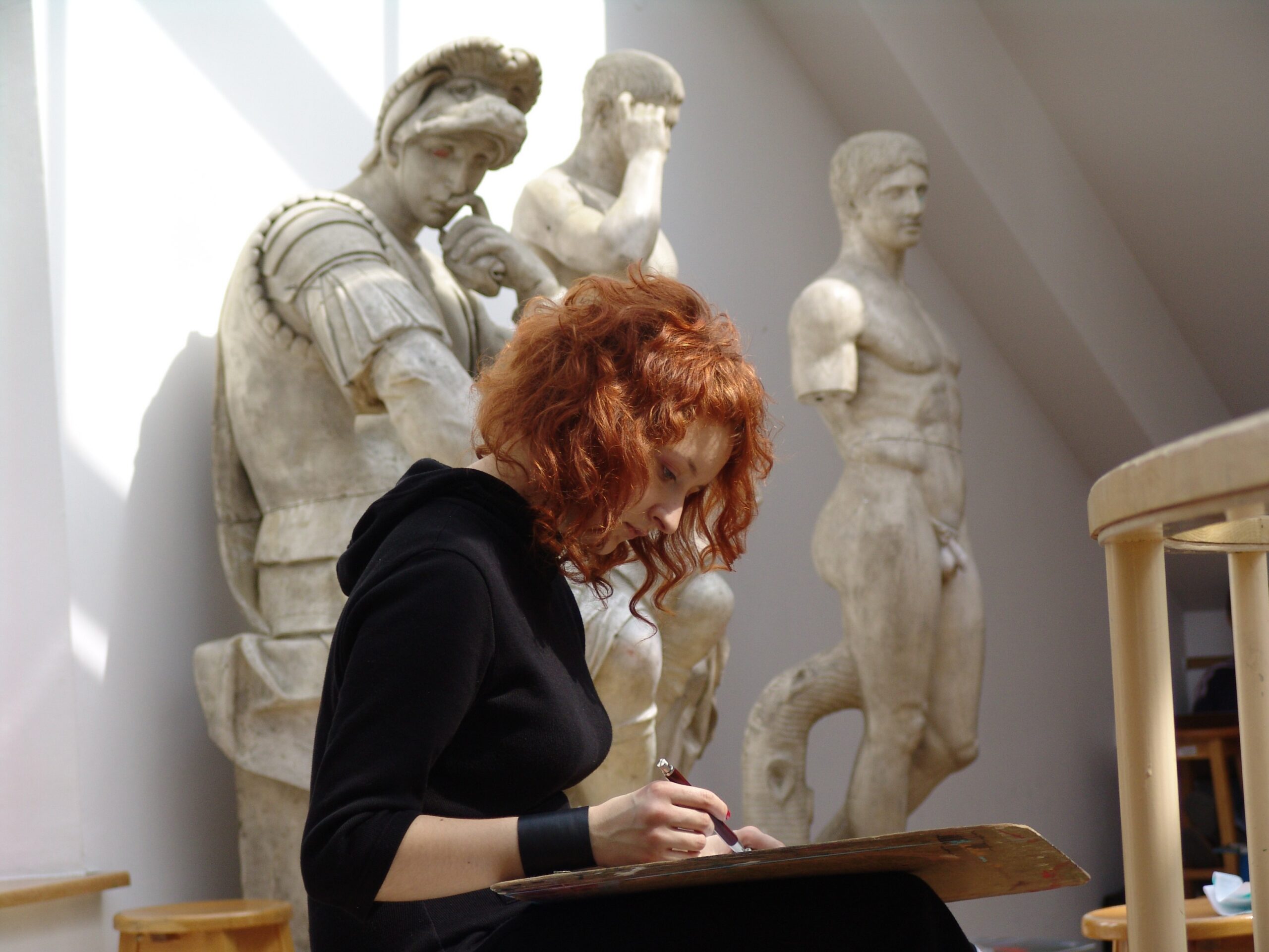 Student drawing a picture during drawing classes at the Faculty of Architecture, Greek-style sculptures in the background