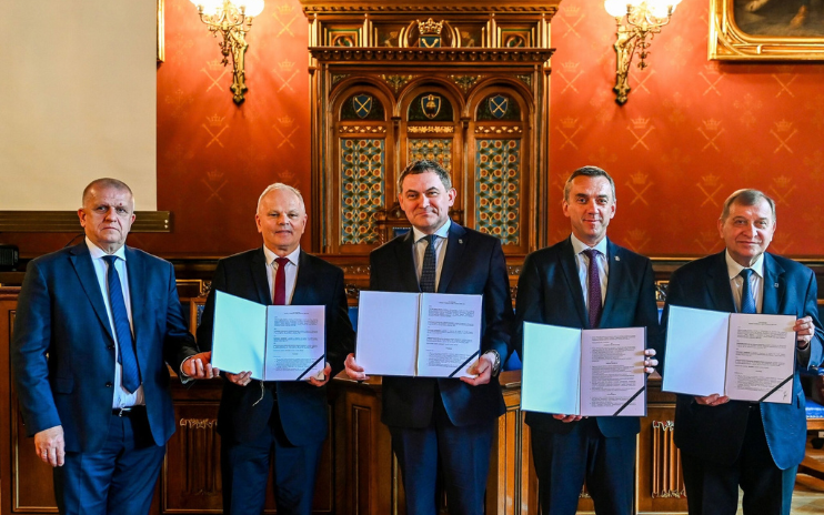 dolina_kwantowa Pięciu mężczyzn w garniturach - rektorów krakowskich uczelni - pozuje do wspólnego zdjęcia. W dłoniach trzymają otwarte teczki z dokumentami
