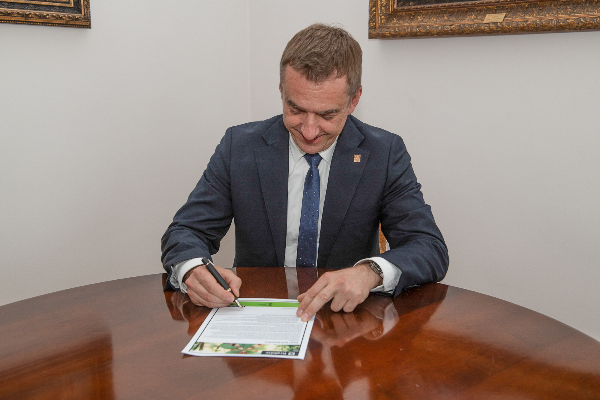 Rektor Andrzej Szarata pochyla się nad dokumentem, który podpisuje